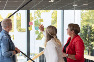 teamfoto met post its voor een glazen wand in een kantoor, samenwerken