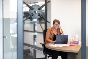 Een foto van coach irma aan het werk achter de laptop op kantoor